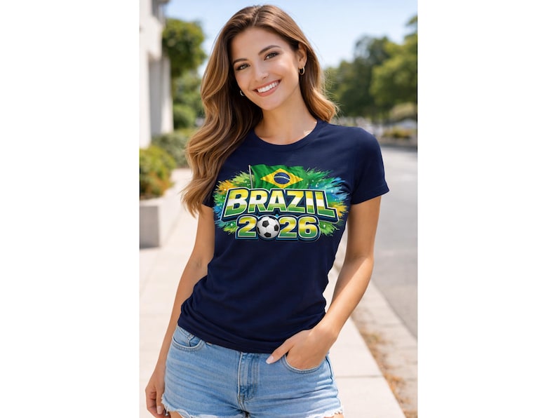 May include: A navy blue t-shirt featuring the text "BRAZIL 2026" in green and yellow, a football, and the Brazilian flag. The t-shirt is short-sleeved with a crew neck.