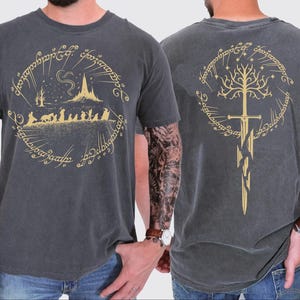 two different views of a man wearing a gray t-shirt with a graphic design featuring a castle, a tree, and a sword.