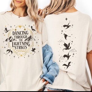 two women wearing white t-shirts with a graphic design on the front and back.
