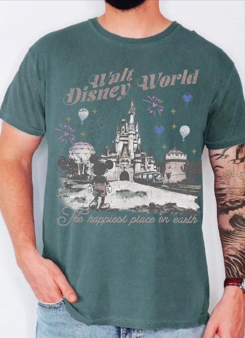 A man wearing a green t-shirt with a graphic design depicting Mickey Mouse and various Disney landmarks, including the Eiffel Tower and the castle.