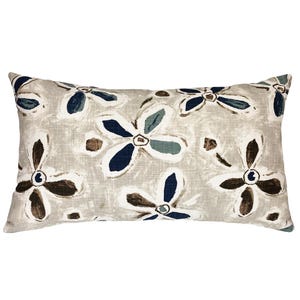 May include: Rectangular decorative pillow with a floral pattern. The pillow features a light beige background with a repeating design of stylized flowers in shades of navy blue, brown, and teal. The pillow is designed for home decor.