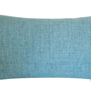 May include: A rectangular turquoise pillow with a textured fabric appearance. The pillow is a solid color and has a simple, minimalist design. The pillow is likely used for home decor.