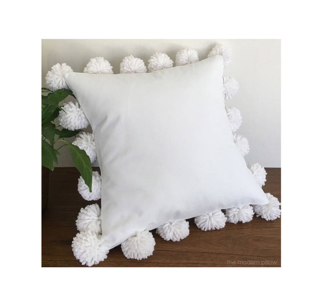 White pillow shop with pom poms