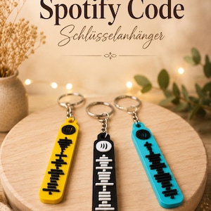 Könnte beinhalten: Drei Spotify Code Schlüsselanhänger in Gelb, Schwarz und Blau, jeweils mit einem silbernen Schlüsselring. Die Schlüsselanhänger werden auf einer Holzoberfläche präsentiert, mit dem Text "Personalized Spotify Code Schlüsselanhänger" im Hintergrund.