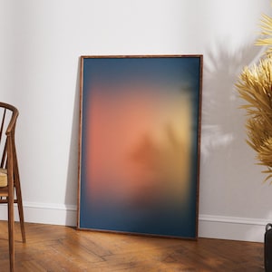 Peut inclure: Une impression d'art abstrait encadrée avec un dégradé de couleurs. L'œuvre présente un mélange de teintes bleues, oranges et jaunes, encadré dans un cadre en bois brun foncé. L'impression est appuyée contre un mur blanc.