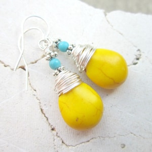 May include: A pair of yellow teardrop-shaped earrings with turquoise beads and silver wire wrapping.