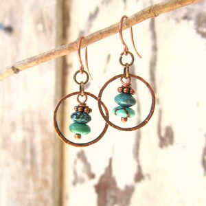 May include: Copper hoop earrings with turquoise gemstone beads. The hoops are hammered and have a rustic look.