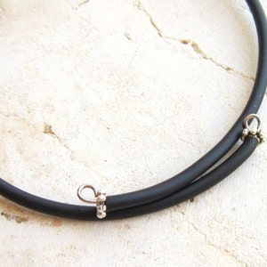 May include: A black rubber choker necklace with silver metal clasps.