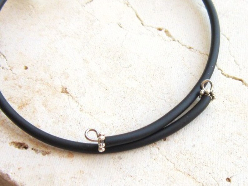 May include: A black rubber choker necklace with silver metal clasps.
