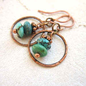 May include: Copper hoop earrings with turquoise stones. The earrings have a hammered texture and are a bohemian style.