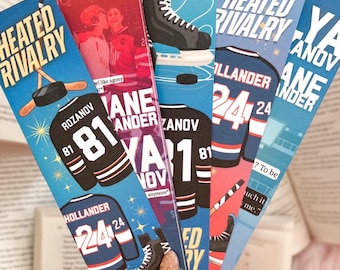 May include: A collection of colorful bookmarks with hockey-themed designs. Each bookmark features a jersey with a player's name and number, along with hockey skates and the text "Heated Rivalry."