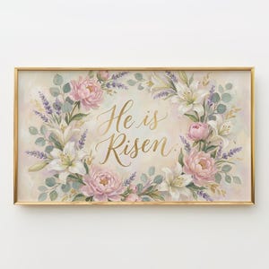 May include: A framed floral print with the words "He is Risen" in gold script. The artwork features a wreath of pink peonies, white lilies, and lavender sprigs against a soft, pastel background. The frame is gold.