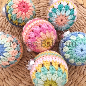 May include: Six crocheted ornaments in various colors, including pink, blue, green, and yellow. Each ornament has a different pattern and is decorated with a silver hanger.