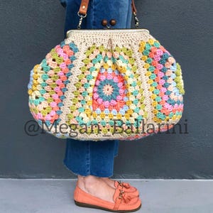 Puede incluir: Un bolso de ganchillo de cuadrados de la abuela con cierre de broche. El bolso está hecho con una variedad de colores pastel, incluyendo rosa, azul, verde y amarillo. El bolso lo lleva una persona que lleva pantalones vaqueros azules.