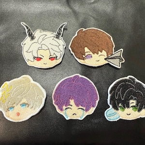 May include: Set of five embroidered patches featuring anime-style character faces. Each patch has a different hair color and facial expression. One character has horns, another has a paper airplane, and another is crying.