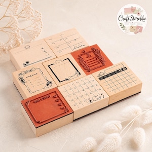 May include: A collection of eight square wooden rubber stamps arranged in a grid. The stamps feature various designs including a weekly planner, a monthly calendar, a memo list with floral borders, a clipboard, and a decorative frame with text.