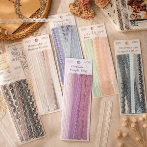 May include: A selection of pastel-coloured lace strips, including purple, pink, blue, and green. Each pack contains 40 pieces and is labelled with names such as "Glorious Purple Ting" and "Exquisite Day Floral Lace". Ideal for craft projects.