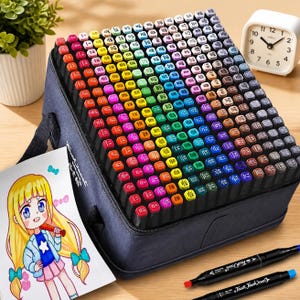 May include: A large collection of multi-coloured art markers organised in a black carrying case. The set includes a wide spectrum of hues with numbered caps. A drawing of a blonde character and two loose black markers are placed in the foreground.
