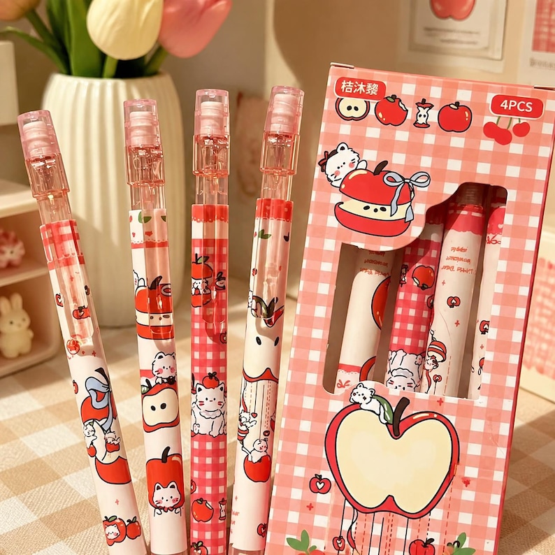 May include: Four mechanical pencils with white barrels featuring red apple and white cat illustrations, paired with a pink and white checkered cardboard box labeled 4PCS and Chinese text, displaying matching apple and cat graphic designs.