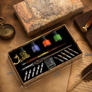 K&ouml;nnte beinhalten: Ein Kalligraphie-Set in einer 24cm x 14cm x 4,5cm gro&szlig;en Box mit einem Holzstift, elf Metallfedern, einer goldfarbenen Stiftablage, einem kleinen Glastintenfa&szlig; und vier Tintenflaschen in Schwarz, Blau, Orange und Gr&uuml;n mit der Aufschrift The Feather Pen.