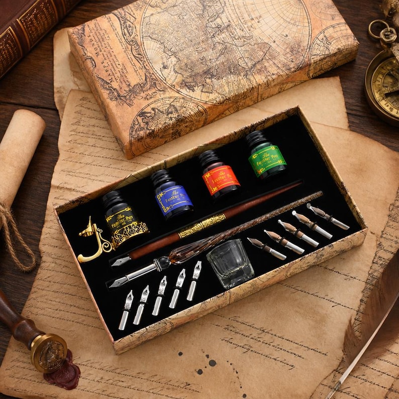 K&ouml;nnte beinhalten: Ein Kalligraphie-Set in einer rechteckigen Schachtel mit Vintage-Landkarten-Aufdruck. Das Set enth&auml;lt einen braunen Holz-Federhalter, eine goldfarbene Stiftablage, ein kleines Glas-Tintenfass, drei Tintenflaschen und elf verschiedene Metallfedern.