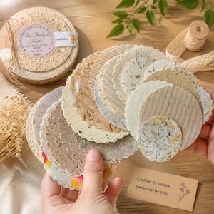 May include: A selection of circular paper coasters in shades of beige, brown, and cream, with diverse textures and some scalloped edges. A stack is tied with twine and labelled "The Imilese Feaster". A card reads "Crafted by nature, perfected by you."