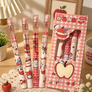May include: Four pens with a white and pink gingham pattern featuring cartoon cats and red apples, accompanied by a matching rectangular cardboard box labeled 4PCS. The pens have clear plastic caps and clips, and the box displays apple graphics.