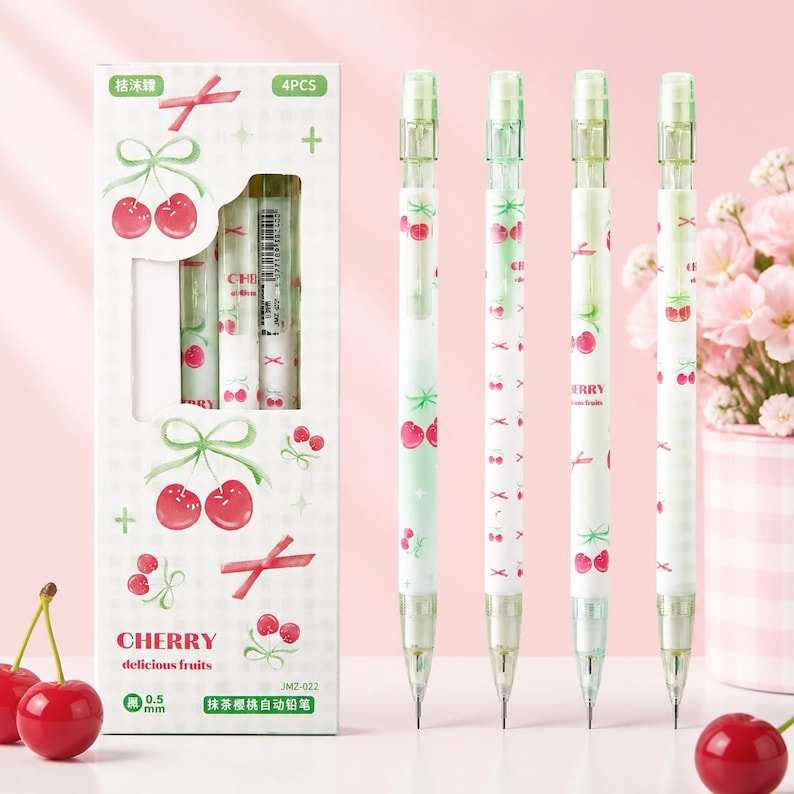 May include: A set of four mechanical pencils with a 0.5 mm lead size, featuring a white and light green barrel decorated with red cherry illustrations and pink ribbons. The packaging box displays the text CHERRY delicious fruits and 4PCS.
