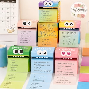Puede incluir: Un conjunto de seis dispensadores de notas adhesivas cuadrados y coloridos con forma de monstruos de dibujos animados con ojos expresivos. Cada dispensador presenta un color degradado único y dispensa notas de papel impresas con fórmulas matemáticas y texto educativo.