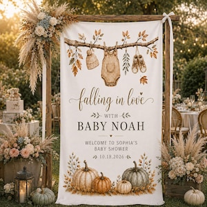 May include: A vertical white fabric banner featuring a watercolor illustration of a tree branch with a baby hat, onesie, and booties hanging from it. The text reads: falling in love WITH BABY NOAH WELCOME TO SOPHIA'S BABY SHOWER 10.18.2026, with pumpkins.
