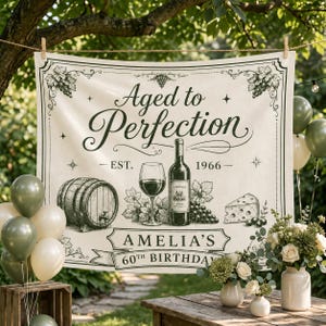 May include: A rectangular fabric banner featuring the text Aged to Perfection, Est. 1966, and Amelia's 60th Birthday. The design includes black line art illustrations of a wine barrel, a wine glass, a wine bottle, grapes, and a wedge of cheese.