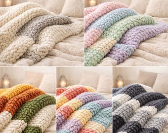Könnte beinhalten: Eine Auswahl an grob gestrickten Decken in verschiedenen Farben, darunter Creme, Grau, Rosa, Grün, Gelb, Orange und Blau. Die Decken sind auf einem Bett mit neutralen Kissen und einer strukturierten Tagesdecke drapiert. Das dicke Garn erzeugt eine gemütliche, einladende Ästhetik.