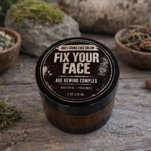 May include: A brown jar of anti-aging face cream with a black lid. The lid features the text "FIX YOUR FACE" and "AGE REWIND COMPLEX". The jar contains 55 ml of cream. The background includes wooden bowls and rocks.