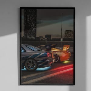 May include: Framed print featuring two sports cars with vibrant lighting effects. One car is silver with blue accents, the other is orange. The background shows a city skyline at night, with red and blue lights illuminating the road.