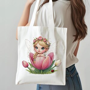 May include: A white canvas tote bag featuring a graphic print of a blonde fairy with a flower crown sitting inside a large pink tulip. The illustration includes green leaves, small white flowers, and a tiny red ladybird at the base of the flower.