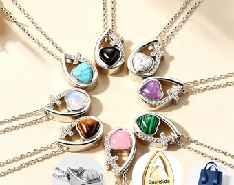 May include: A collection of silver-toned teardrop-shaped cremation urn necklaces, each featuring a small heart-shaped stone in various colors including turquoise, black, white, purple, green, and pink, with a cross detail and a delicate chain.