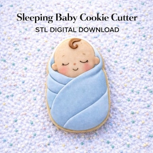 May include: A cookie cutter in the shape of a sleeping baby wrapped in a blue blanket. The baby has closed eyes, rosy cheeks, and a swirl of brown hair. The text "Sleeping Baby Cookie Cutter" and "STL DIGITAL DOWNLOAD" are at the top.