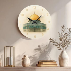 May include: Cream-faced wall clock with a gold-domed building illustration. The clock has black hands and gold numerals. A decorative item for the home, with a diameter of approximately 30 cm.