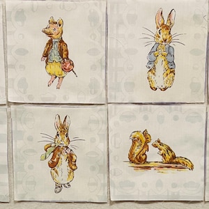 May include: Eight square fabric patches featuring watercolor-style illustrations of Beatrix Potter characters. The designs include rabbits in pink coats, a mouse, Peter Rabbit, three mice, a duck in a bonnet, a squirrel, and three kittens in clothing.