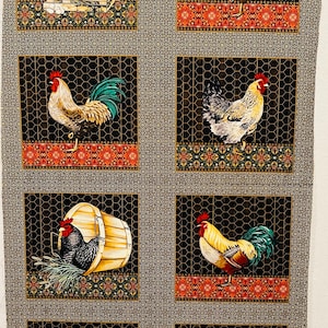 Op de afbeelding: Een stoffen paneel met een herhalend patroon van kippen in kooien. De kippen zijn in verschillende kleuren en poses afgebeeld, waaronder hanen en hennen. De kooien zijn gemaakt van zwart draadgaas en hebben een decoratieve rand. De stof is bedrukt op een zwarte achtergrond met gouden accenten.