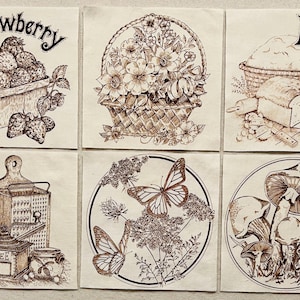 May include: A set of six sepia-toned illustrations. One shows strawberries in a wooden crate with the word "Strawberry". Another depicts a basket of flowers. A third shows bread with the word "Bread". Other illustrations include a coffee grinder, butterflies, and mushrooms.