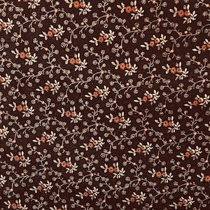 Peut inclure: Un tissu brun avec un motif répétitif de petites fleurs et feuilles blanches et orange.