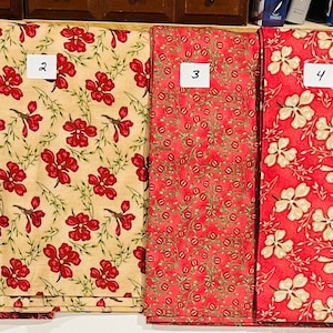 Peut inclure: Quatre échantillons de tissu avec différents motifs floraux. Les échantillons sont numérotés de 1 à 4. Les motifs sont tous rouges et blancs sur un fond beige.