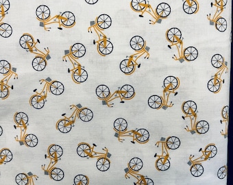 May include: White fabric with a repeating pattern of yellow bicycles. The bicycles have a basket on the front and are facing different directions.