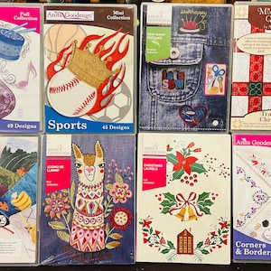 May include: A collection of eight embroidery design books featuring various themes, including musical instruments, sports, llama, Christmas, and corners and borders. Each book has a colorful cover with a unique design and includes the title, "Anita Goodesign", and the number of designs or themes.