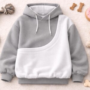 May include: A gray and white pet carrier hoodie with a kangaroo pouch. The image includes dog toys, a plush bear, a donut-shaped toy, and a bowl of pet food. The hoodie has a drawstring hood and is designed for carrying small pets.