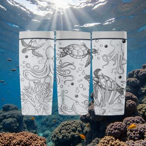 May include: Three white water bottles featuring black line drawings of marine life, such as turtles and octopuses. The bottles have silver lids and the word "owala" is visible. The background depicts an underwater scene with coral and sunlight.