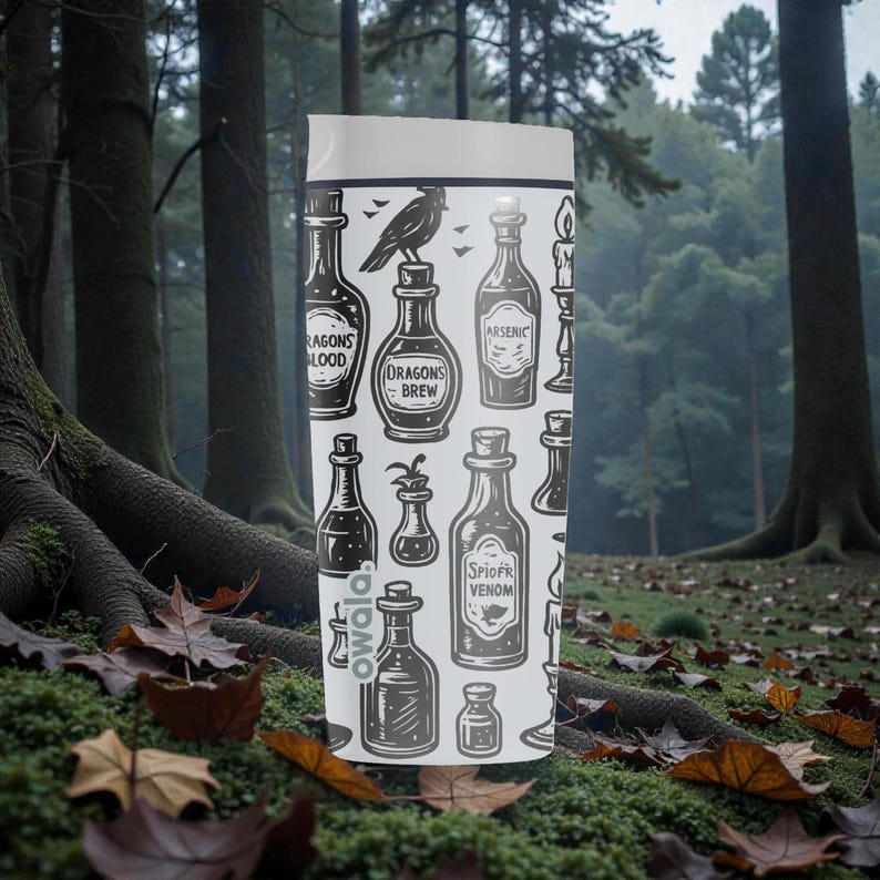 K&ouml;nnte beinhalten: Eine wei&szlig;e Owala-Trinkflasche mit einem sich wiederholenden Muster aus Zaubertr&auml;nken, einem Raben und Kerzen. Die Flaschen sind mit Namen wie "Drachenblut" und "Spinnengift" beschriftet. Die Flasche befindet sich vor einem Waldhintergrund.