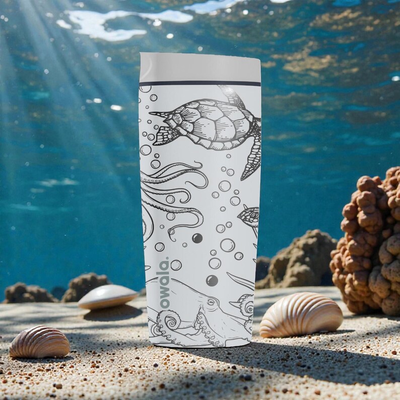 May include: White water bottle featuring a black and white illustration of marine life, such as a turtle and octopus. The bottle has a white lid and the word "owala" is printed on the side. The background shows an underwater scene with sand and seashells.