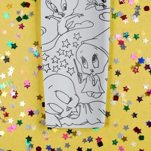 May include: A white rectangular object featuring black line art of cartoon characters, including Tweety Bird, stars, and other whimsical designs. The background is yellow with colorful star-shaped confetti.